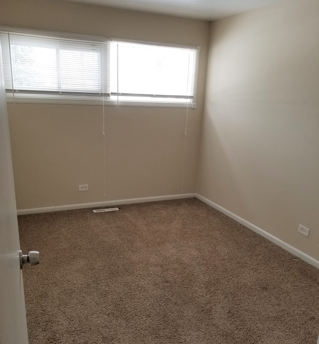 an empty room with a window and a carpet