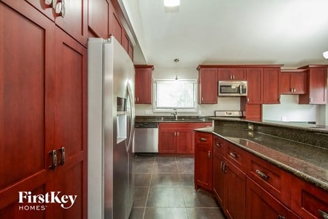 a kitchen with red cabinets and a stainless steel refrigerator