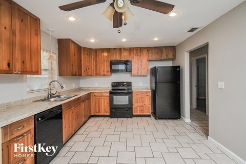 A kitchen with wooden cabinets and black appliances.