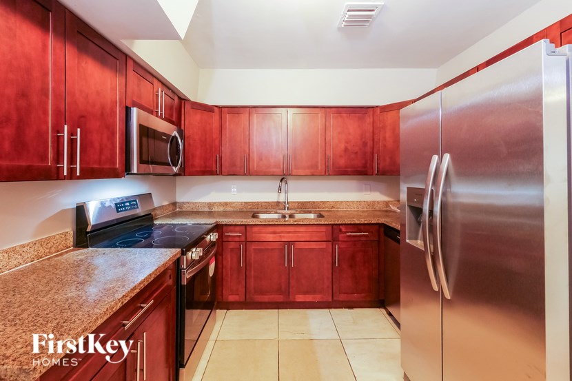A kitchen with red cabinets and a stainless steel refrigerator.