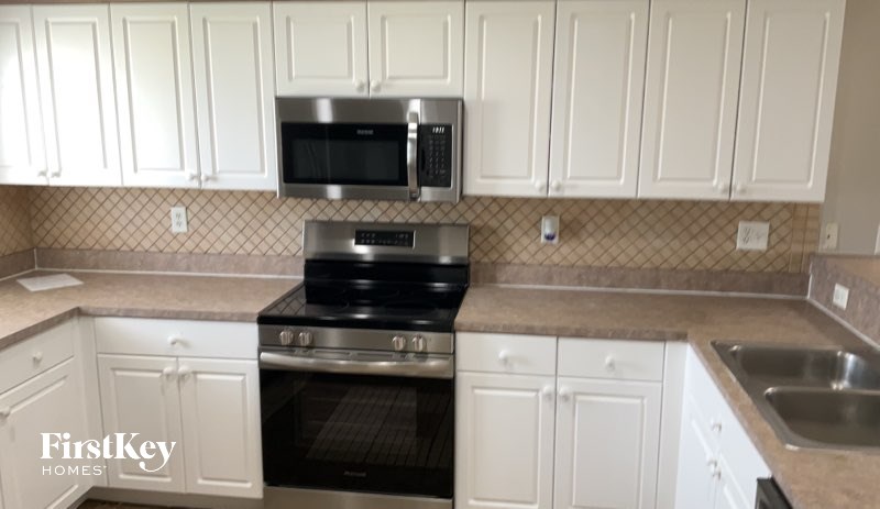 A kitchen with white cabinets and a black stove top oven.