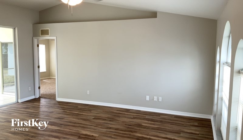 A room with wooden floors and a chandelier is shown.