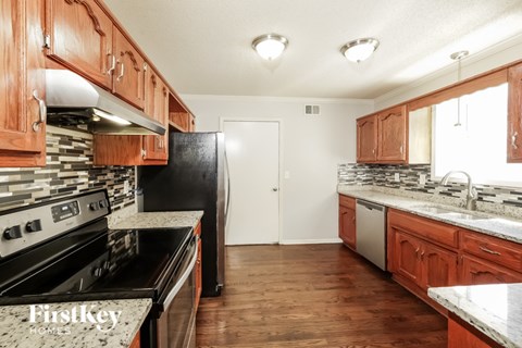 A kitchen with wooden cabinets and a black refrigerator.