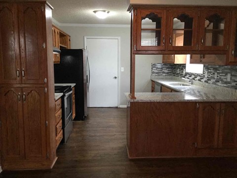 A kitchen with wooden cabinets and a black fridge.