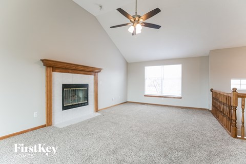 A spacious room with a fireplace and a ceiling fan.