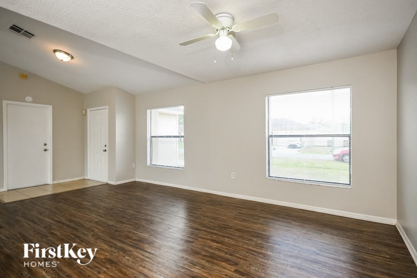 an empty living room with a ceiling fan and a window