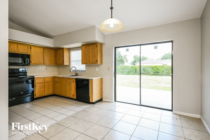 a kitchen with black appliances and wooden cabinets and a sliding glass door