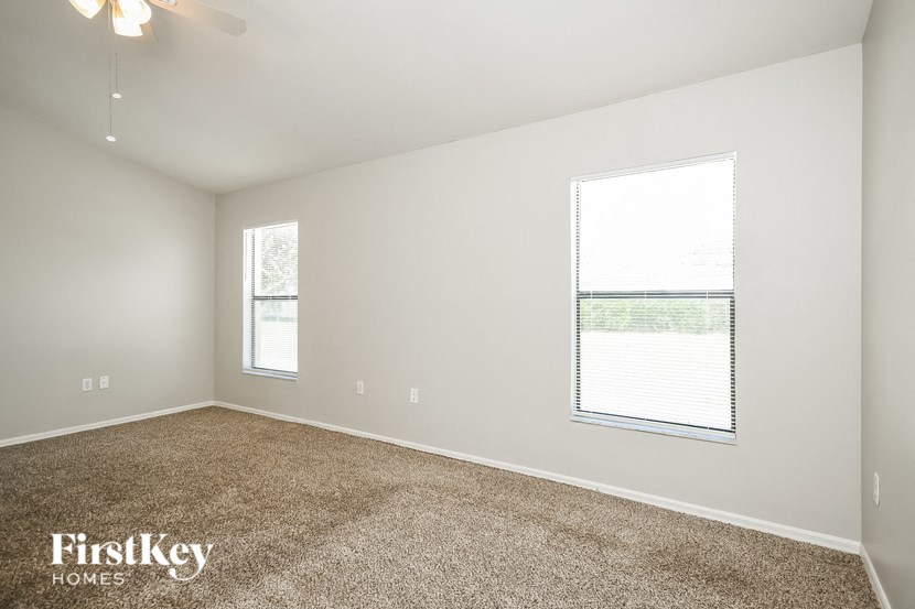 a bedroom with carpet and two windows