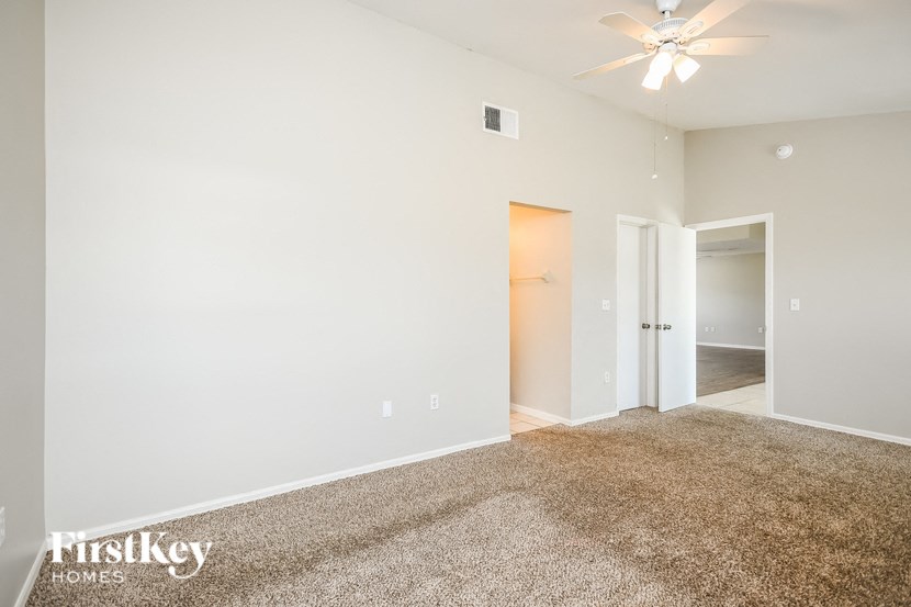 a spacious living room with carpet and a ceiling fan