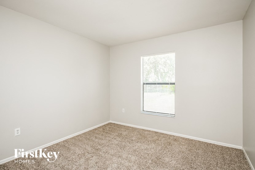 a bedroom with a window and carpeted floor