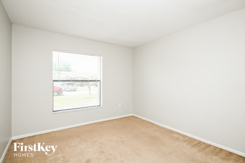 a bedroom with a window and a carpeted floor