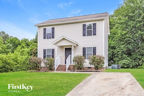 A two-story house with a white front porch and a driveway.