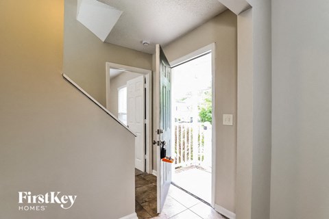 A hallway with a white door leading to a backyard.