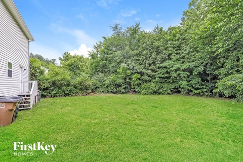 A lush green yard with a house and trees in the background.