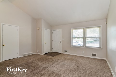 the living room of a house with carpet and a window