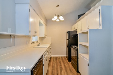 a kitchen with white counters and white cabinets and a black refrigerator