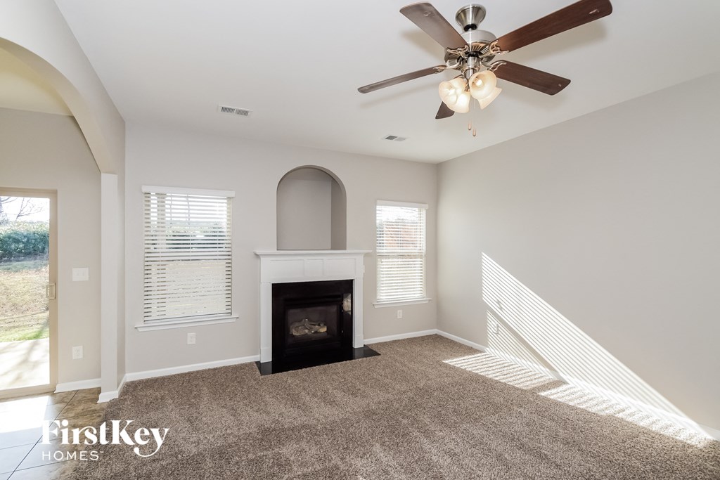 a living room with a fireplace and a ceiling fan