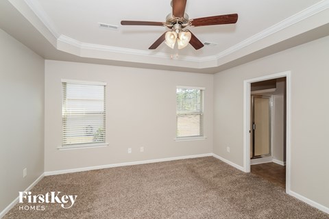 the spacious living room with ceiling fan and carpet