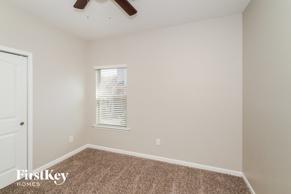 a room with carpet and a window and a ceiling fan