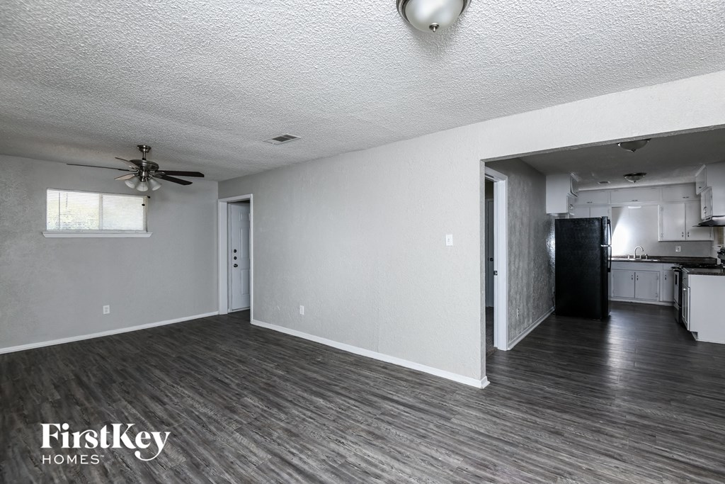 an empty living room and kitchen with a ceiling fan