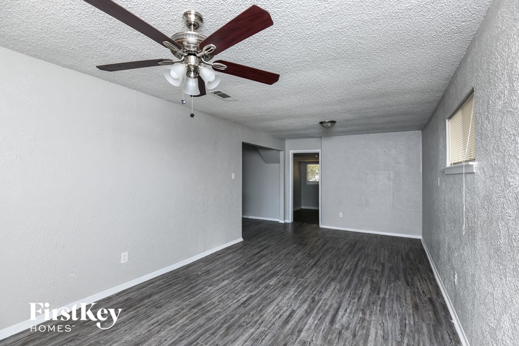 the living room of an empty house with a ceiling fan