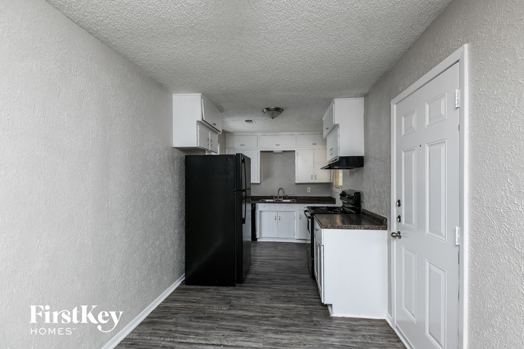 a kitchen with white cabinets and a black refrigerator