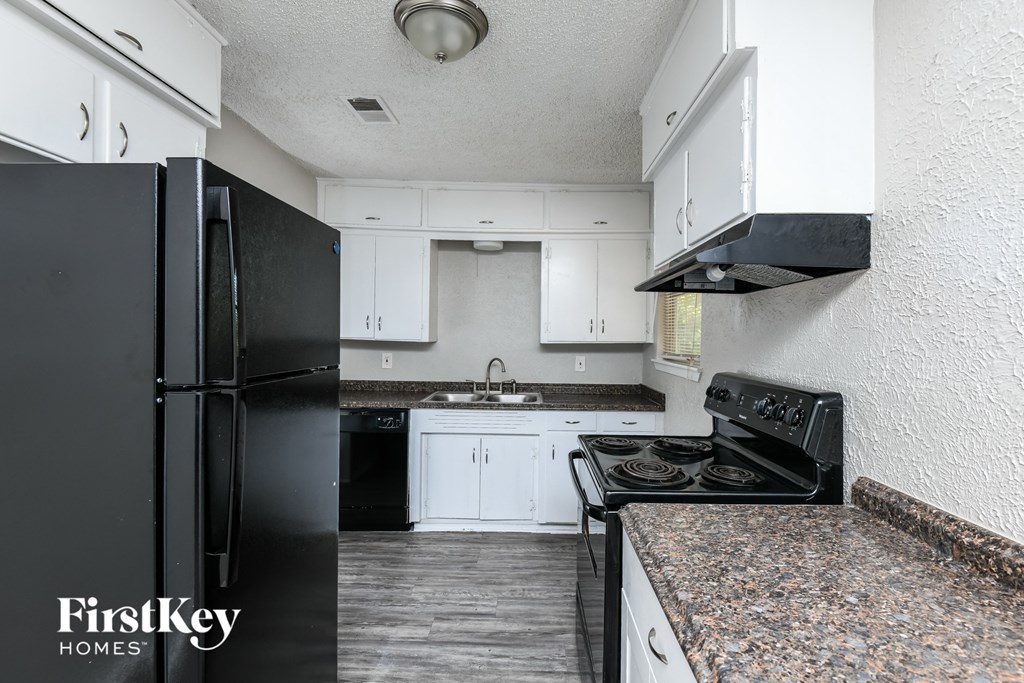 a kitchen with white cabinets and black appliances