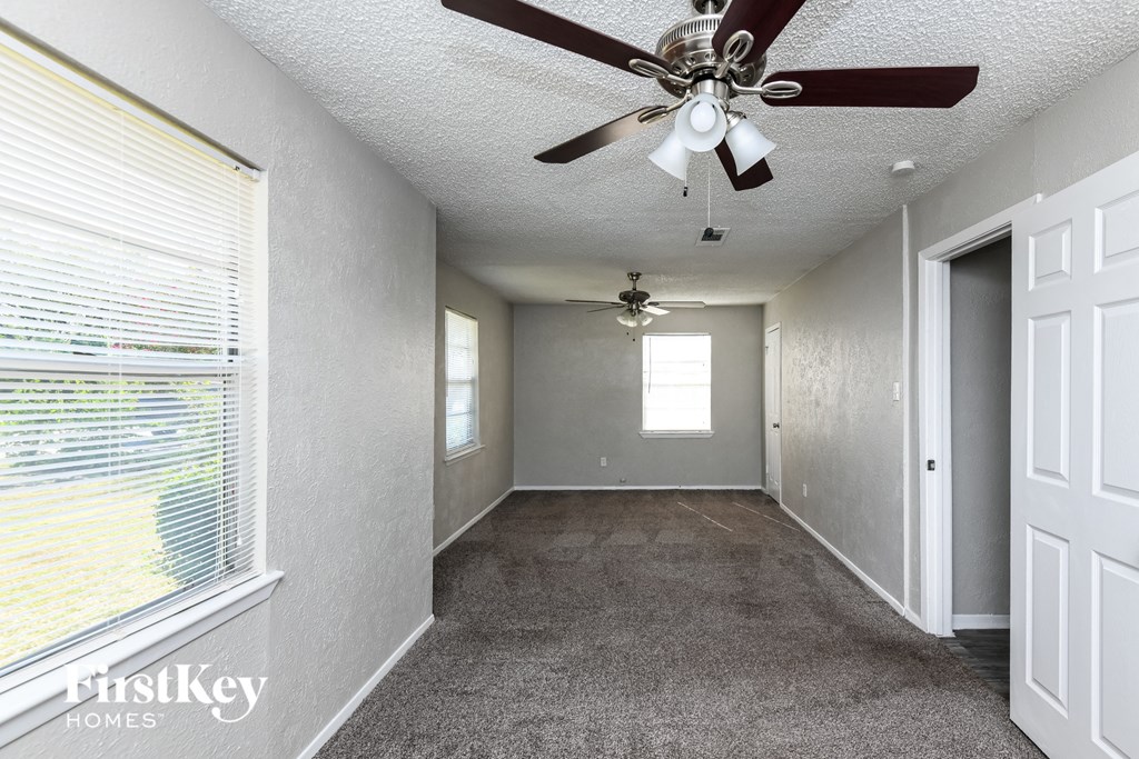 a carpeted hallway with a ceiling fan and a window