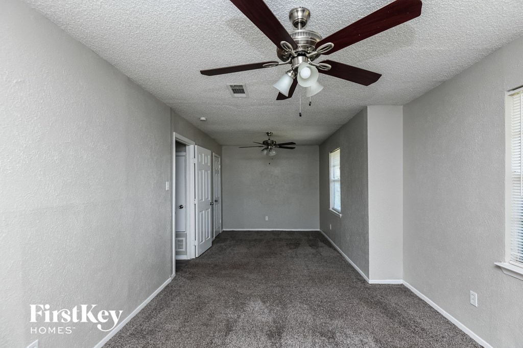a carpeted living room with a ceiling fan
