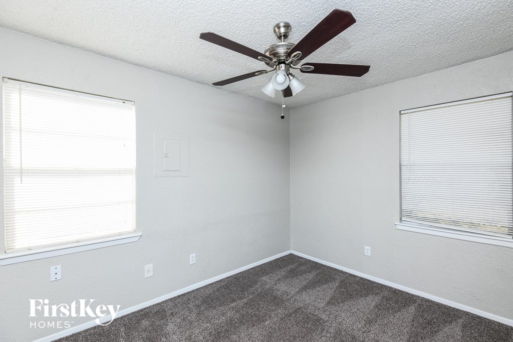 a bedroom with a ceiling fan and two windows