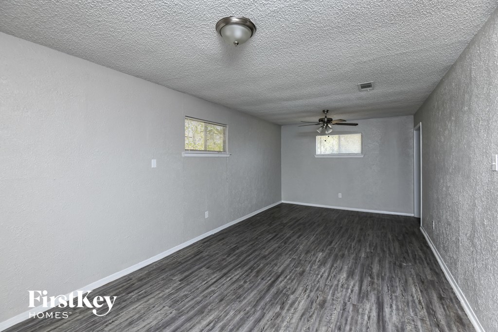 an empty living room with wood floors and a ceiling fan