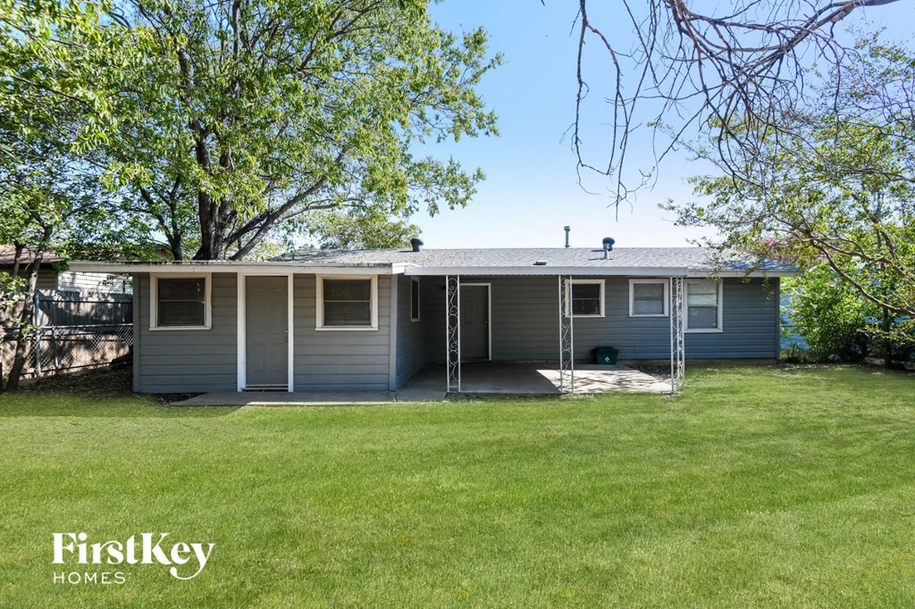a blue house with a lawn and trees
