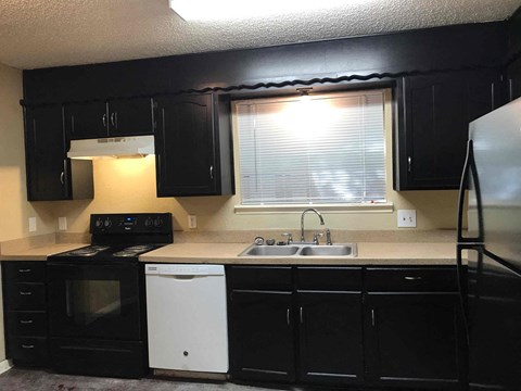 A kitchen with black cabinets and a white dishwasher.