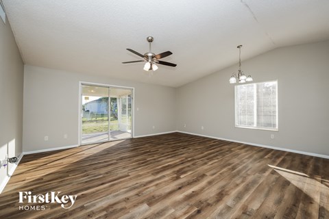 A spacious room with wooden flooring and a ceiling fan.