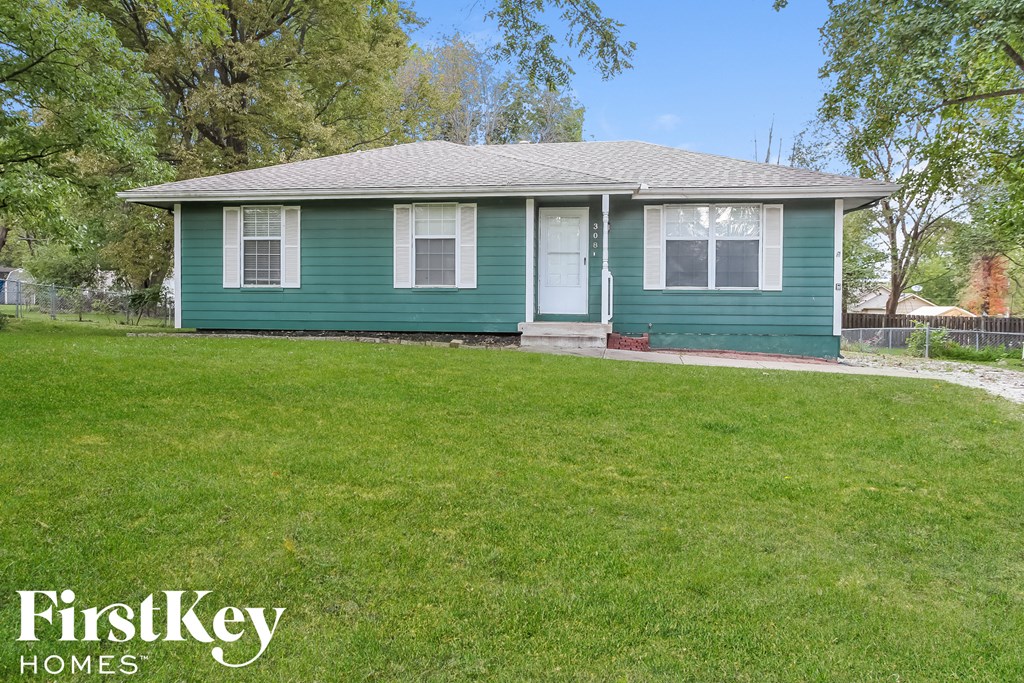 A green house with a white door and windows is for sale.