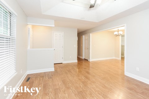 A spacious room with wooden flooring and white walls.