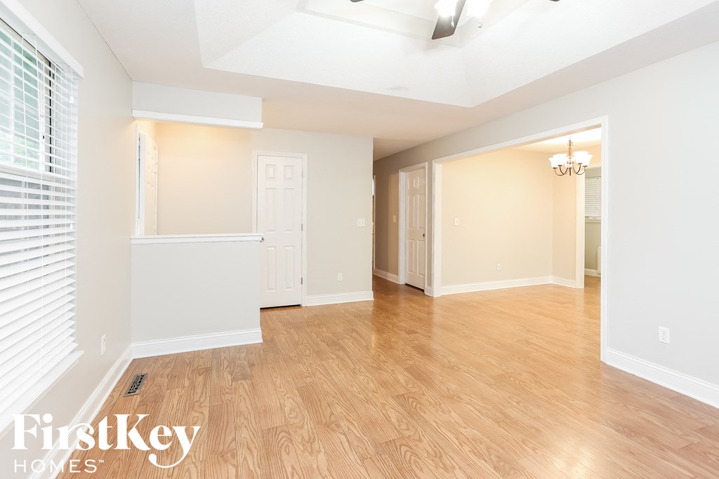 A spacious room with wooden flooring and white walls.