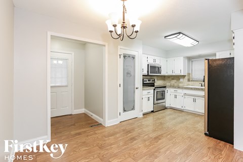 a renovated kitchen with white cabinets and a wooden floor