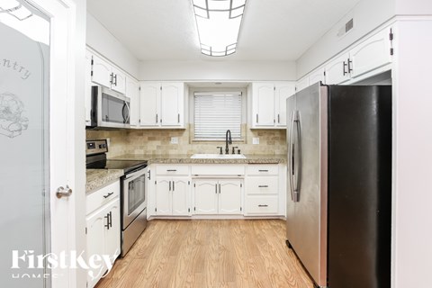 A kitchen with white cabinets and a black refrigerator.