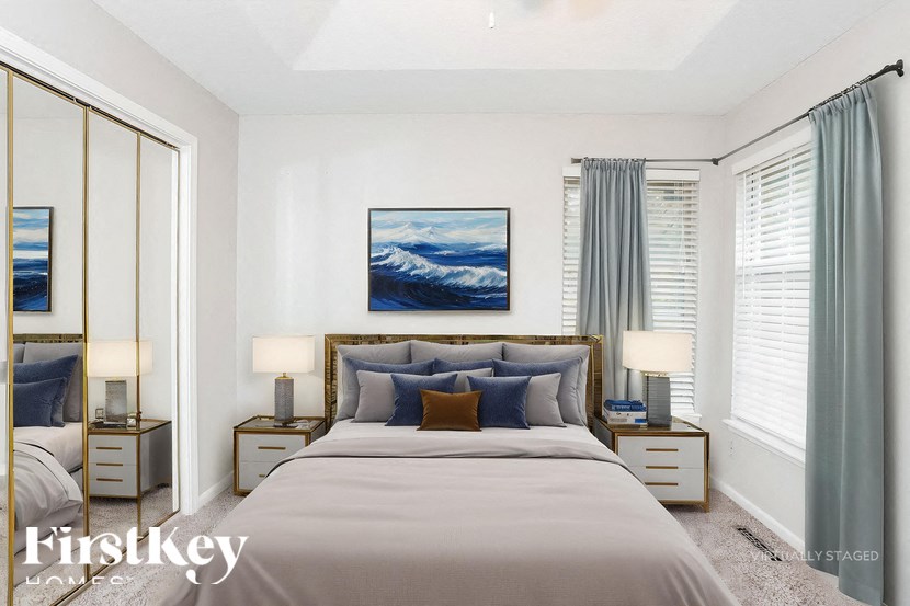 A bedroom with a large bed, two nightstands, and a painting on the wall.