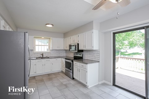 a kitchen with white cabinets and stainless steel appliances and a sliding glass door