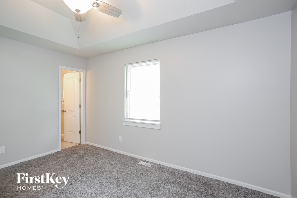 a bedroom with white walls and a ceiling fan