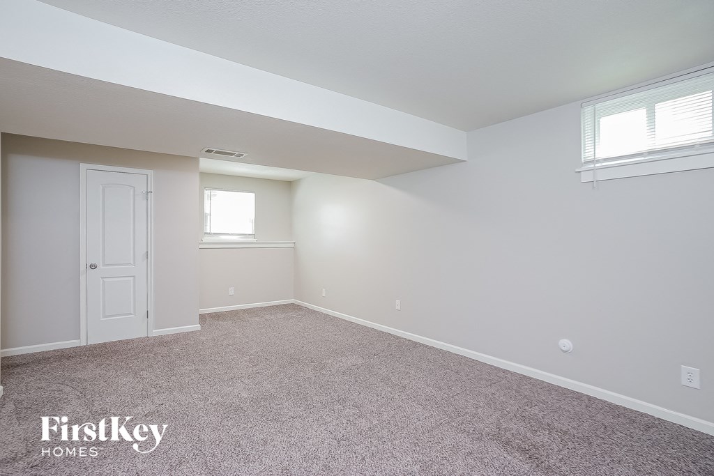a bedroom with carpet and a white door and window