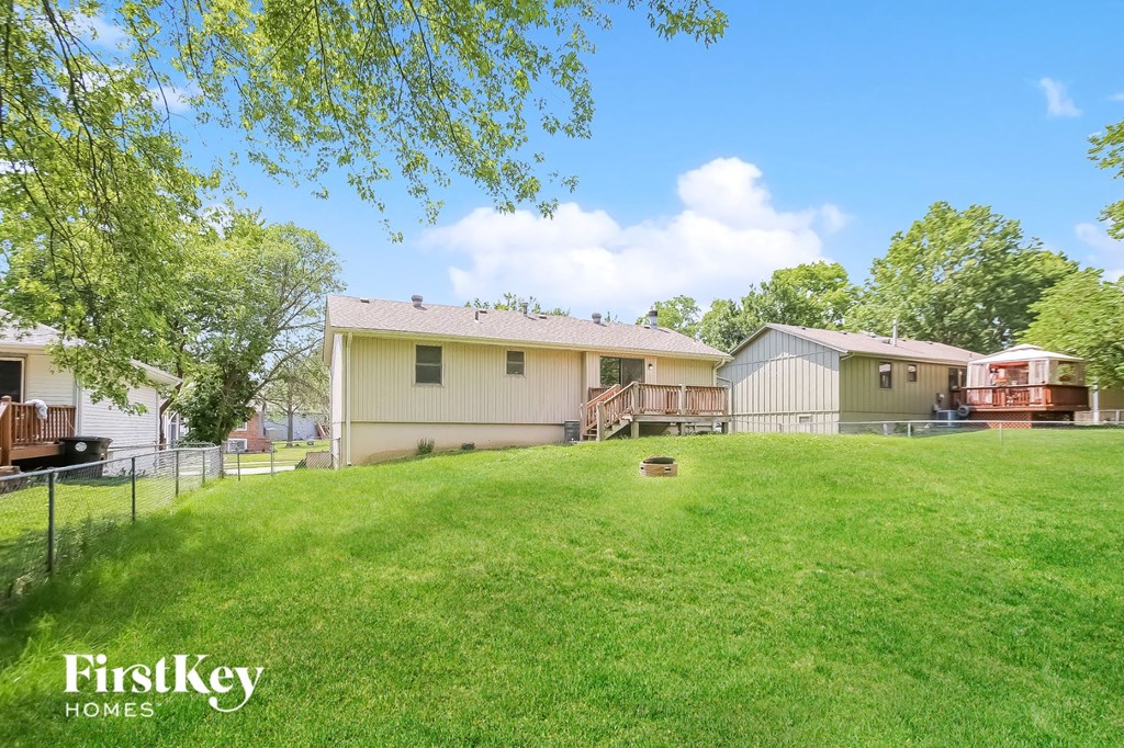 a view of the backyard of a house with a yard and a fence