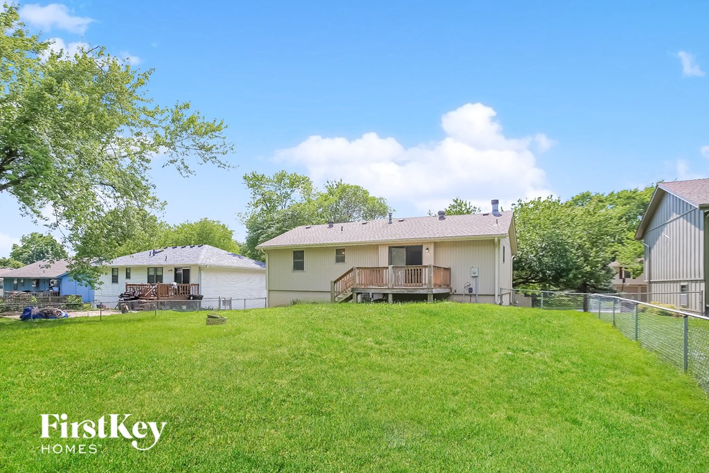 a backyard with a fence and a house on a hill