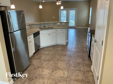 A kitchen with a refrigerator, sink, and cabinets.
