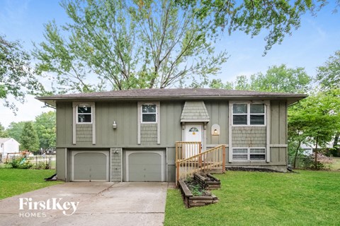 a gray house with two garage doors and a driveway