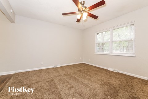an empty living room with a ceiling fan and a window