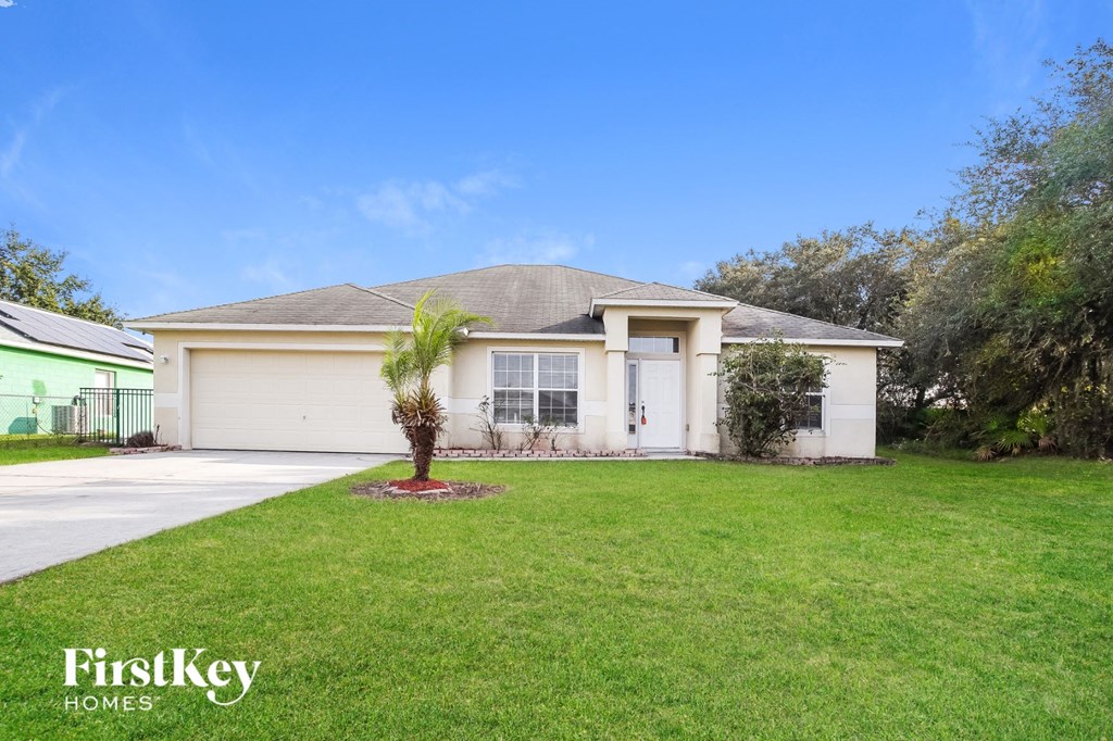 A house with a green lawn and a tree in front of it.