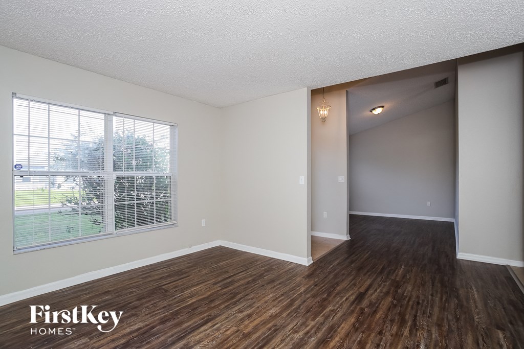 A room with wooden floors and a window overlooking a lawn.